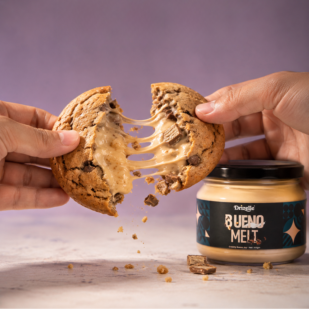 Hands breaking an open chocolate chip cookie with a stretchy caramel pull, with a jar of Delightz Bueno Melt peanut butter sauce in the foreground against a purple background.